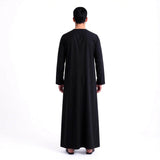 Qamis noir signature Saoudien pour homme de la marque MonQamisHomme, vue en détail sur le tissu et la coupe élégante.