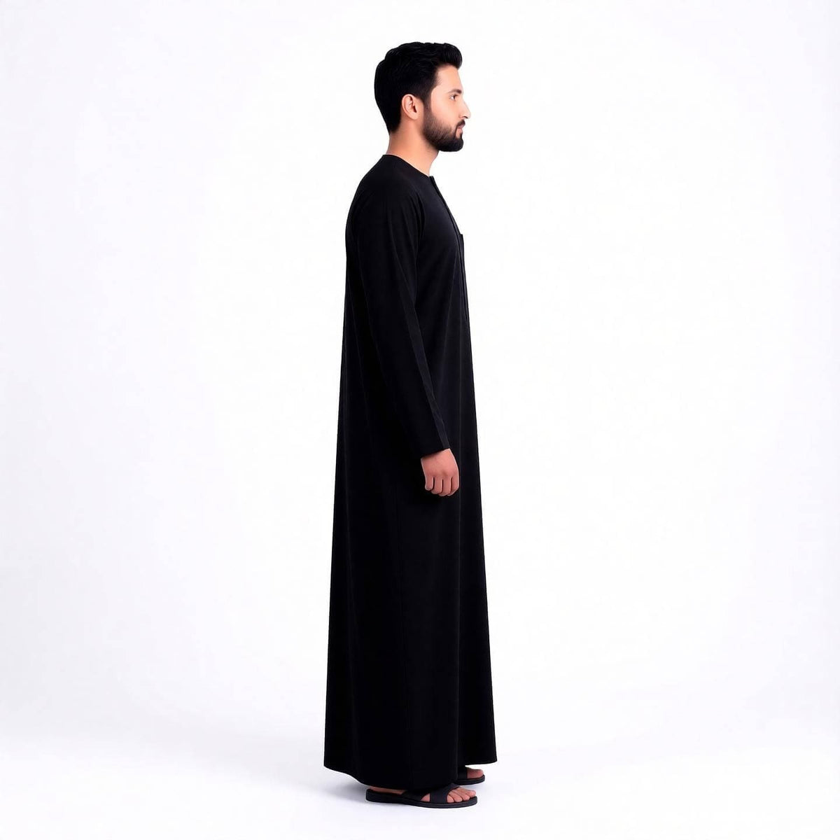 Qamis noir signature saoudien pour homme, vêtement traditionnel élégant, porté par un homme. MonQamisHomme.